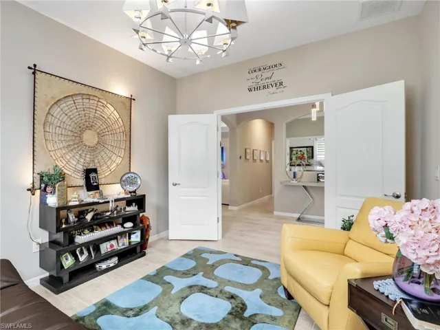 Living area featuring arched walkways, a chandelier, and light wood-type flooring