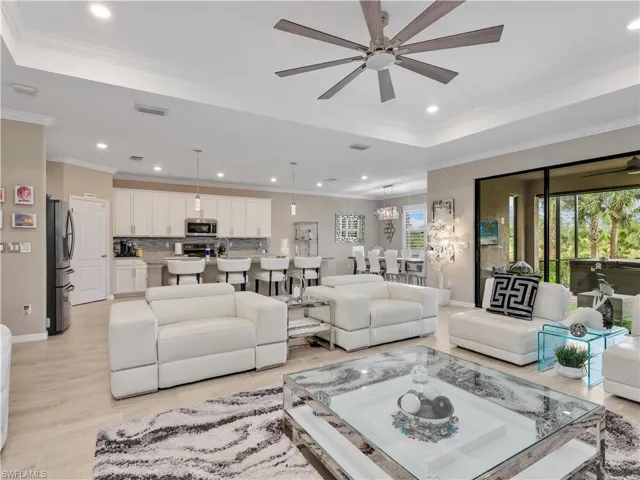 Living area with a ceiling fan, recessed lighting, ornamental molding, light wood-style floors, and a tray ceiling