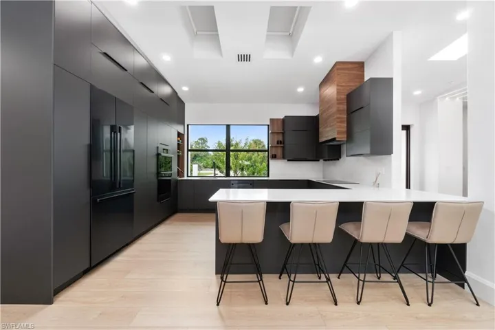 Kitchen featuring a breakfast bar, sink, light hardwood / wood-style floors, high quality fridge, and kitchen peninsula