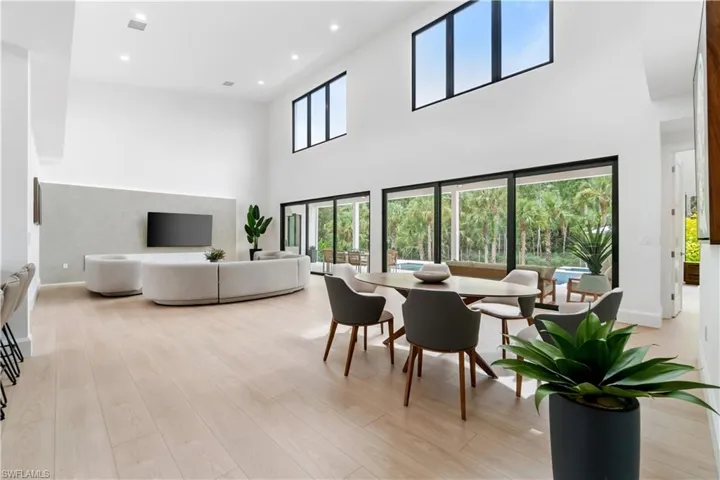 Living room with a wealth of natural light, light hardwood / wood-style flooring, and a high ceiling