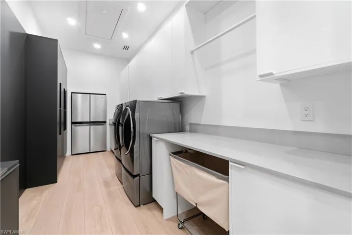 Washroom with light wood-type flooring, cabinets, and independent washer and dryer