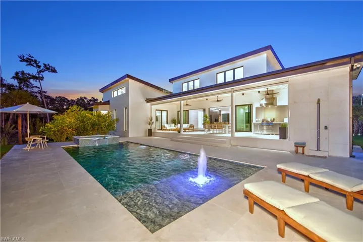 Pool at dusk featuring ceiling fan and a patio