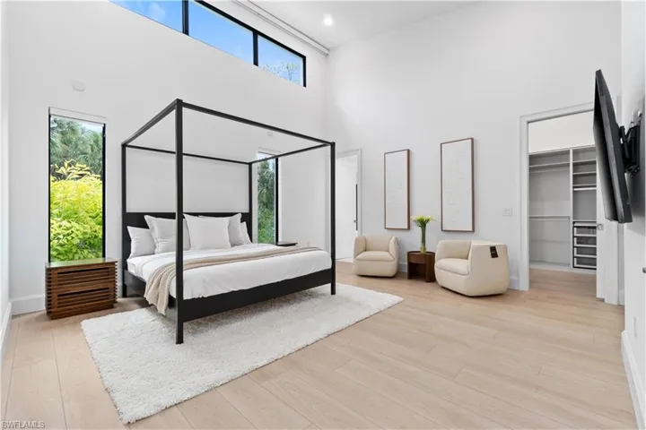 Bedroom with light hardwood / wood-style floors, a spacious closet, and multiple windows