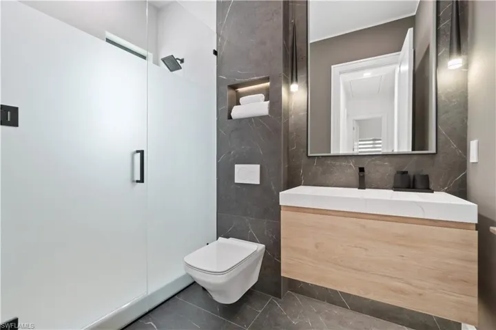 Bathroom with tile patterned flooring, a shower with shower door, dual vanity, and toilet