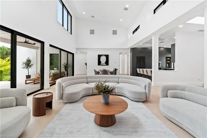 Living room with high vaulted ceiling and light hardwood / wood-style floors