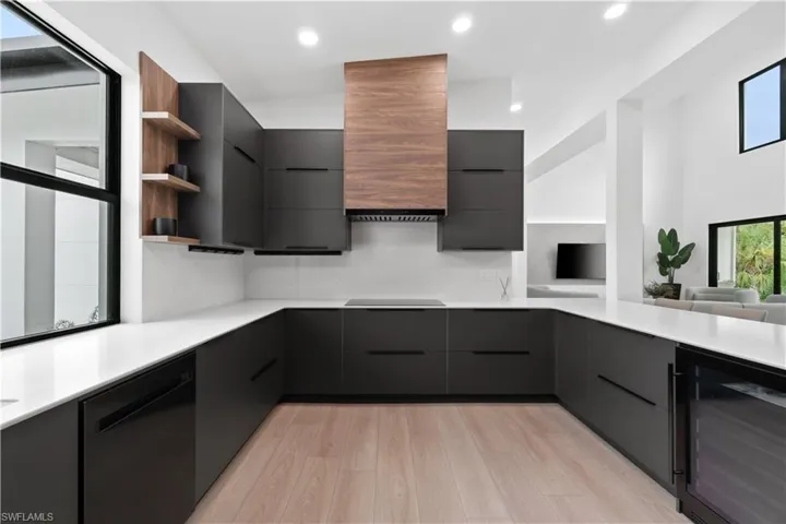 Kitchen with backsplash, light hardwood / wood-style floors, dishwasher, stovetop, and beverage cooler