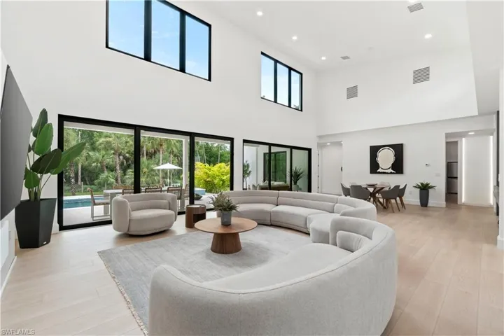 Living room with light wood-type flooring, plenty of natural light, and a high ceiling