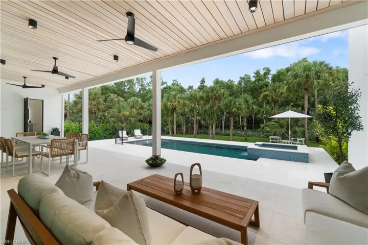 Outdoor area overlooking the pool and preserve with large patio, electric bug screen, outdoor kitchen and full pool bathroom