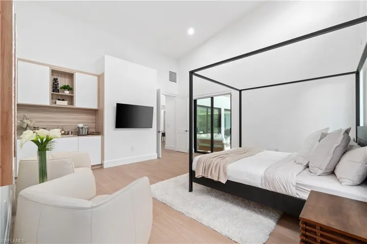 Bedroom featuring access to outside, a towering ceiling, light hardwood / wood-style flooring, and multiple windows