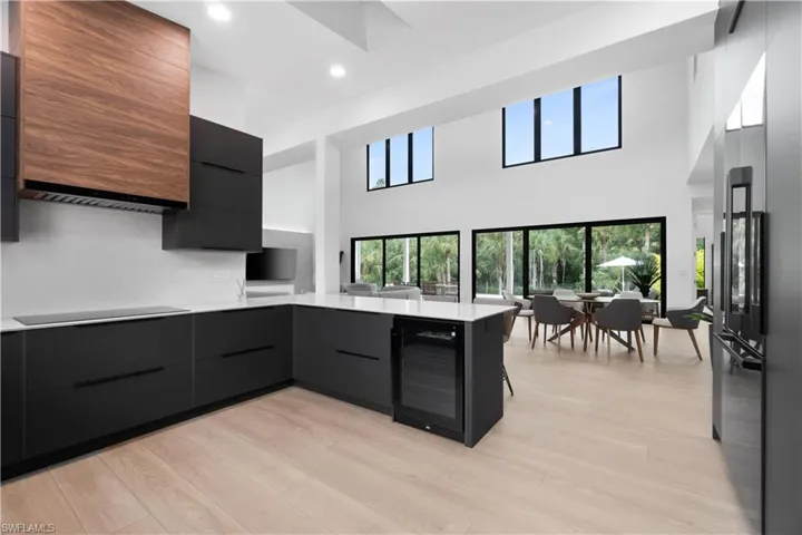 Kitchen with black electric stovetop, kitchen peninsula, light hardwood / wood-style floors, and beverage cooler