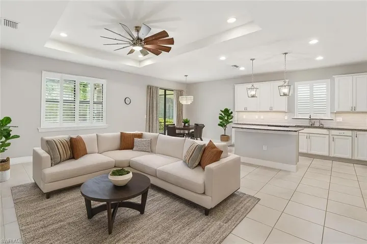 Living area featuring a tray ceiling, plenty of natural light, light tile patterned flooring, and recessed lighting