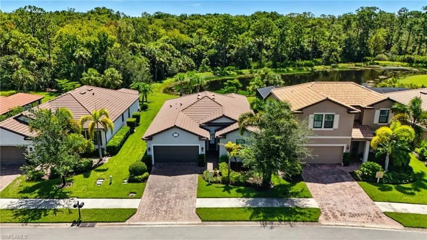 Aerial view of property and surrounding area featuring a nearby body of water and a forest