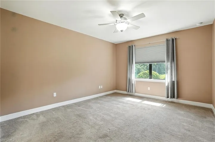 Empty room with light colored carpet and a ceiling fan
