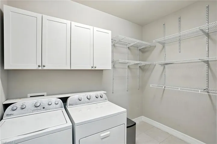 Laundry area featuring cabinet space, light tile patterned floors, and independent washer and dryer