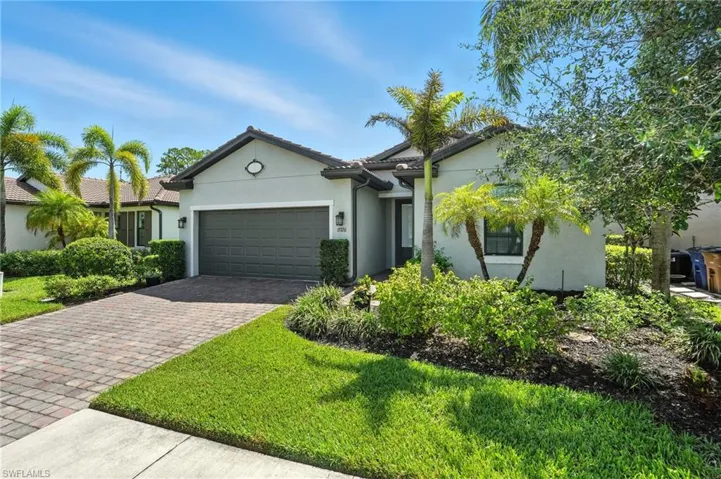 Ranch-style house featuring decorative driveway, stucco siding, a garage, and a front lawn
