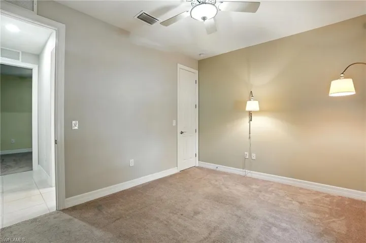 Spare room featuring carpet flooring, a ceiling fan, and tile patterned floors