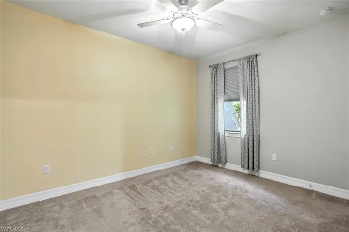 Carpeted empty room featuring baseboards and a ceiling fan