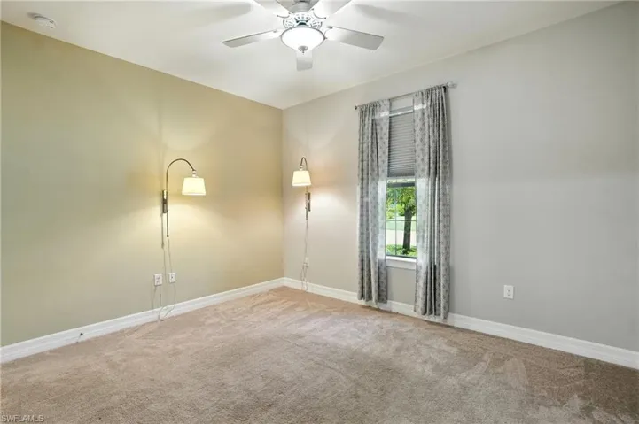 Empty room featuring carpet flooring and a ceiling fan