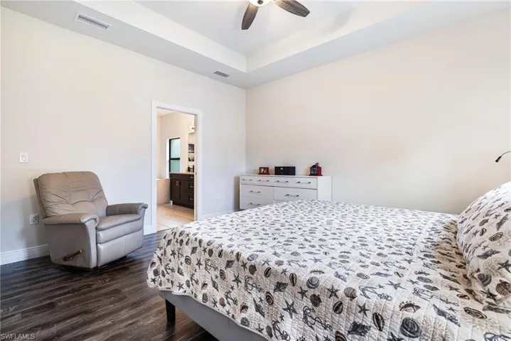 Bedroom featuring ceiling fan, hardwood / wood-style flooring, and ensuite bathroom