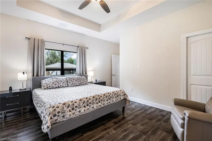 Bedroom featuring a tray ceiling, ceiling fan, and dark hardwood / wood-style floors