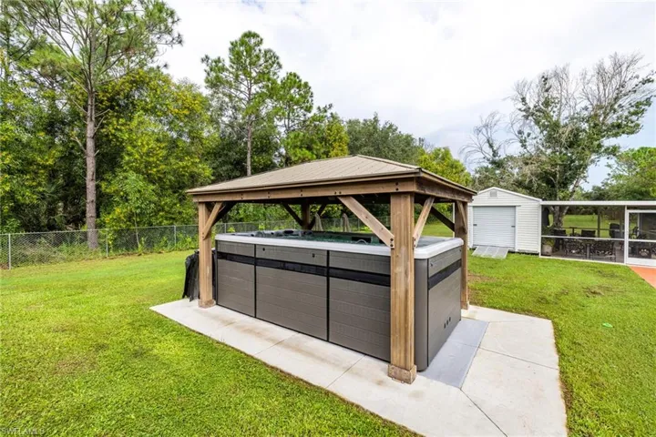 View of yard with a hot tub, an outdoor structure, a gazebo, and a garage