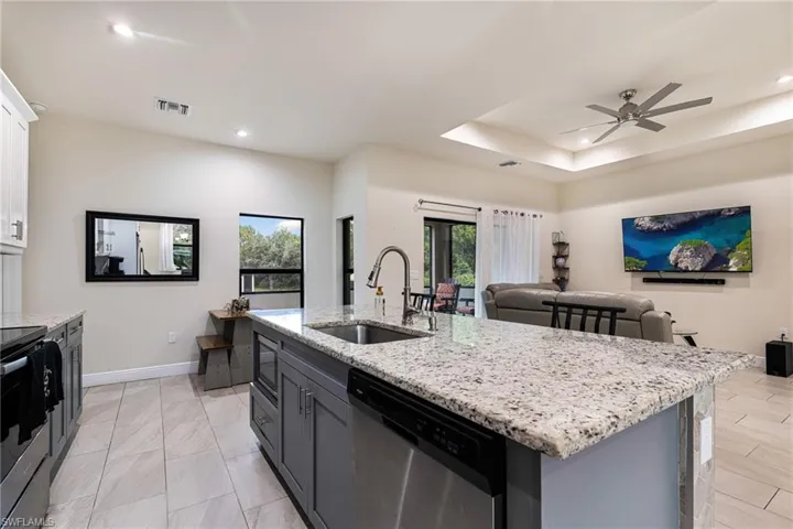 Kitchen featuring a kitchen island with sink, sink, white cabinets, stainless steel appliances, and ceiling fan
