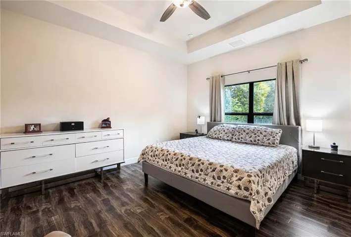 Bedroom featuring a tray ceiling, ceiling fan, and dark hardwood / wood-style floors