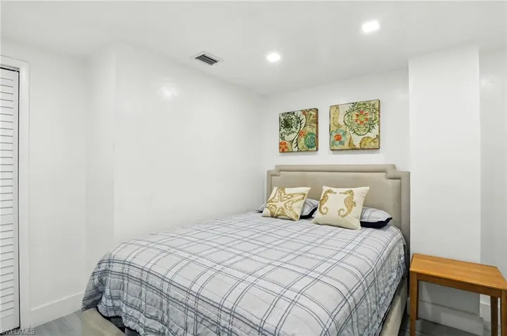 Bedroom featuring a neutral upholstered headboard, recessed lighting, and wood-finish flooring