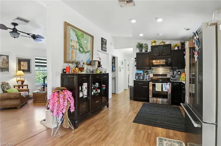 Open-concept kitchen featuring dark cabinetry, stainless steel appliances, and wood-finish flooring