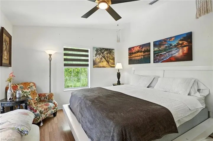 Bedroom featuring wood-finish flooring, a ceiling fan with integrated lighting, and a window with horizontal blinds