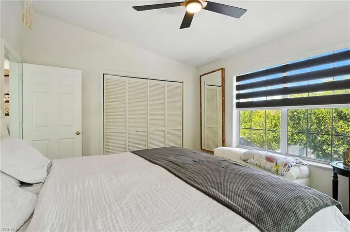 Room featuring a vaulted ceiling with a ceiling fan, a window with horizontal blinds, and a built-in window seat