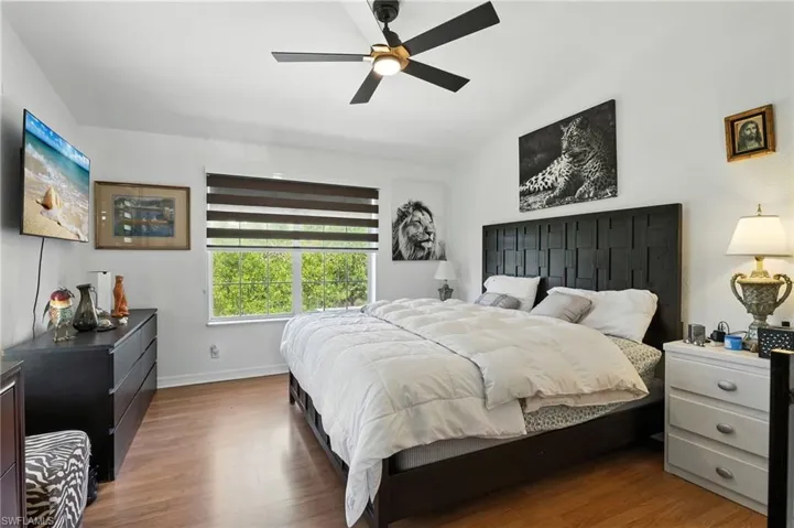 Bright bedroom featuring wood-finish flooring and a contemporary ceiling fan