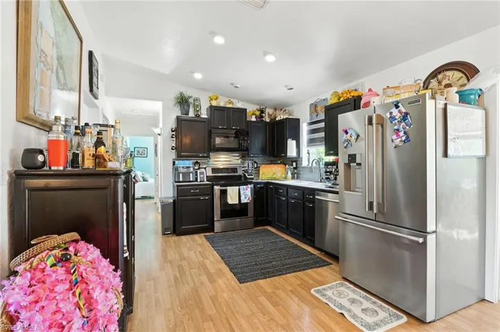 Kitchen featuring wood-finish flooring, dark cabinetry, stainless steel appliances, and recessed lighting