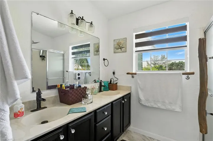 Dual vanity with undermount sinks, dark cabinetry with crystal knobs, and a light-toned countertop