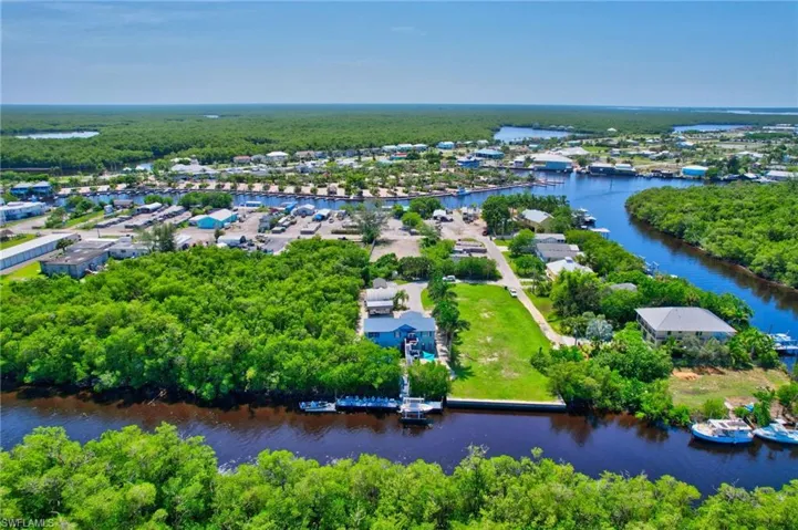 Waterfront property featuring a private boat dock, lush green landscaping, and direct access to a navigable waterway
