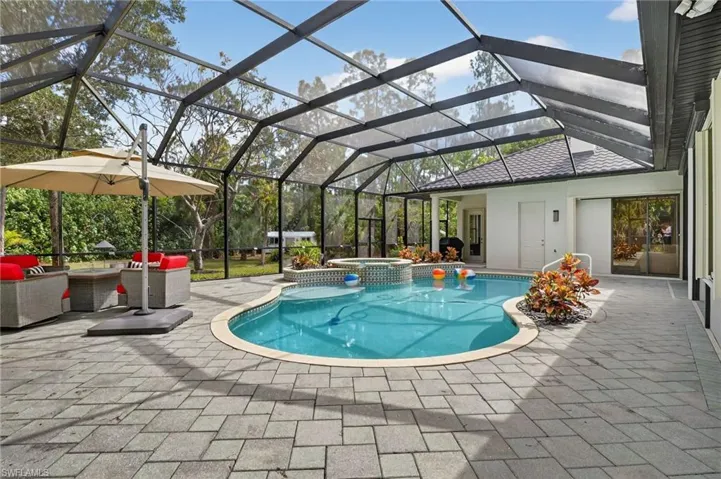 Relaxing pool / spa with a sunroom, a lanai, a patio area, and an outdoor lounge area