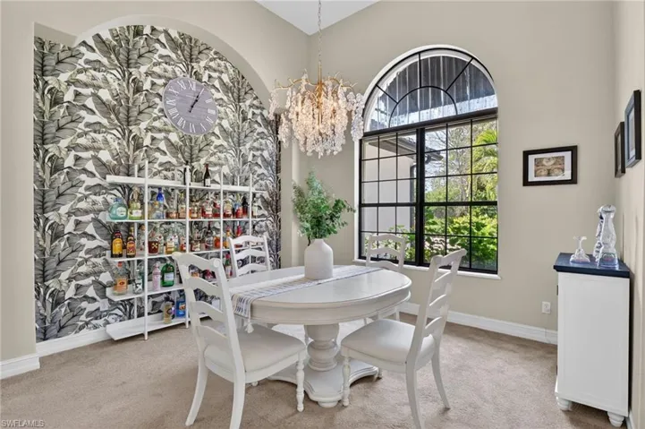 Dining space with hanging lights, light colored carpet, and a high ceiling