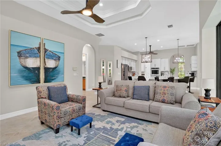 Living area with ceiling fan, arched walkways, crown molding, and suspended lighting