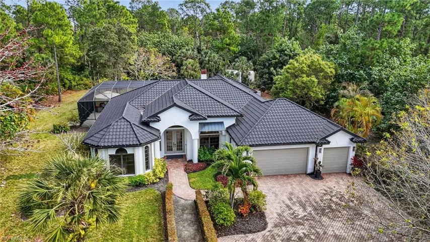 View of front of house featuring french doors, glass enclosure, decorative driveway, and a garage