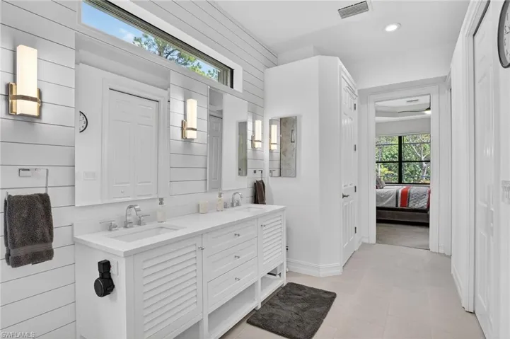 Full bath featuring double vanity, ensuite bath, wooden walls, light tile patterned floors, and a closet