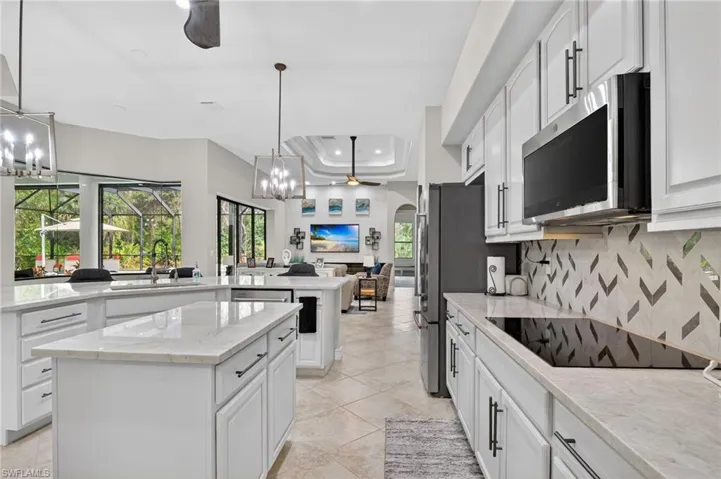Kitchen with a ceiling fan, white cabinetry, a tray ceiling, suspended lighting, and light stone countertops
