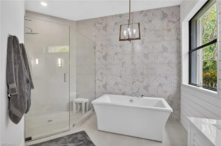 Bathroom with a stall shower, a freestanding tub, tile patterned floors, and vanity
