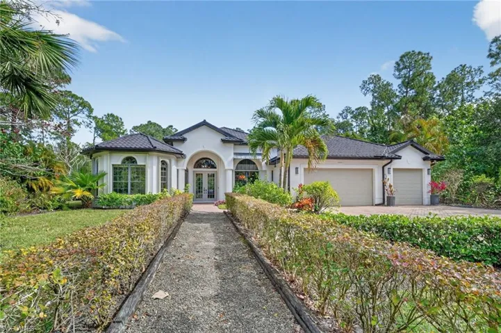 View of front of property featuring french doors, stucco siding, driveway, and an attached garage