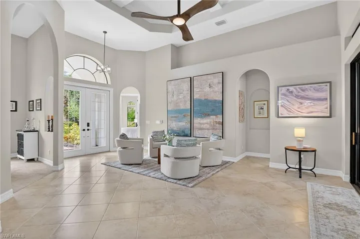 Entrance foyer with arched walkways, a ceiling fan, a high ceiling, suspended lighting, and french doors