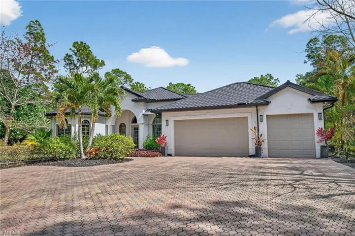 View of front of home with stucco siding, decorative driveway, a tiled roof, and an attached garage