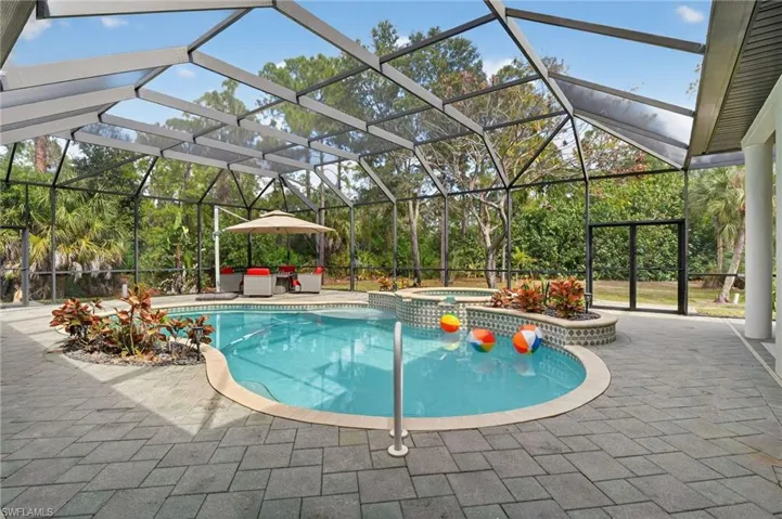 Integrated pool / hot tub featuring a lanai, a sunroom, and a patio area