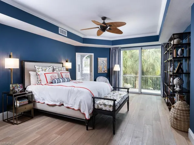 Bedroom with access to outside, wood finished floors, a raised ceiling, and ornamental molding