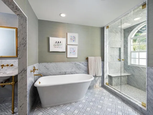 Full bathroom with tile walls, a freestanding bath, a stall shower, and tile patterned floors
