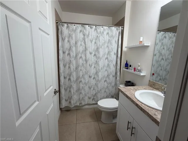 Bathroom featuring a full vanity with a granite-style countertop, undermount sink, and white cabinetry