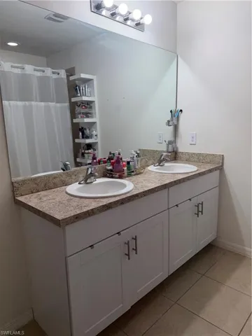 Dual vanity featuring white shaker-style cabinetry, speckled countertops, and undermount sinks